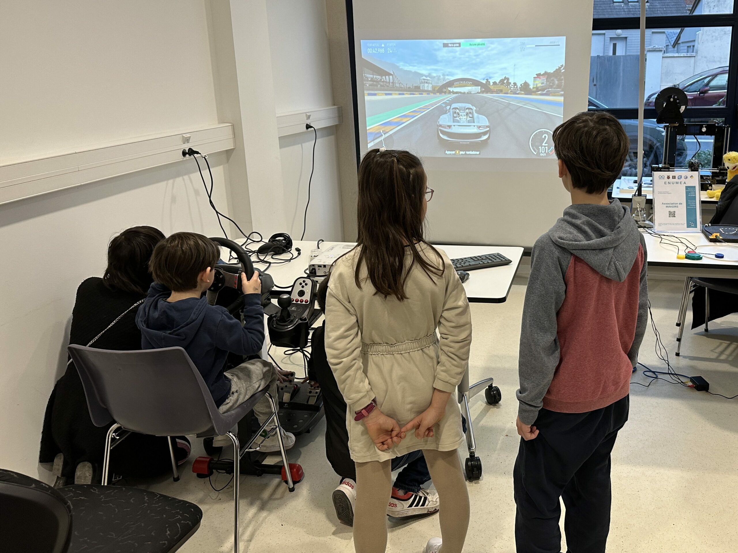 Une jeune fille aide un petit garçon à utiliser les pédales car il est trop petit pour les toucher.